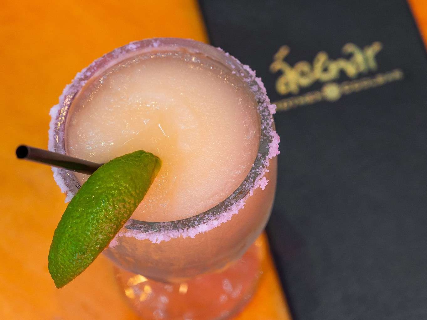 Margarita and menu on orange table
